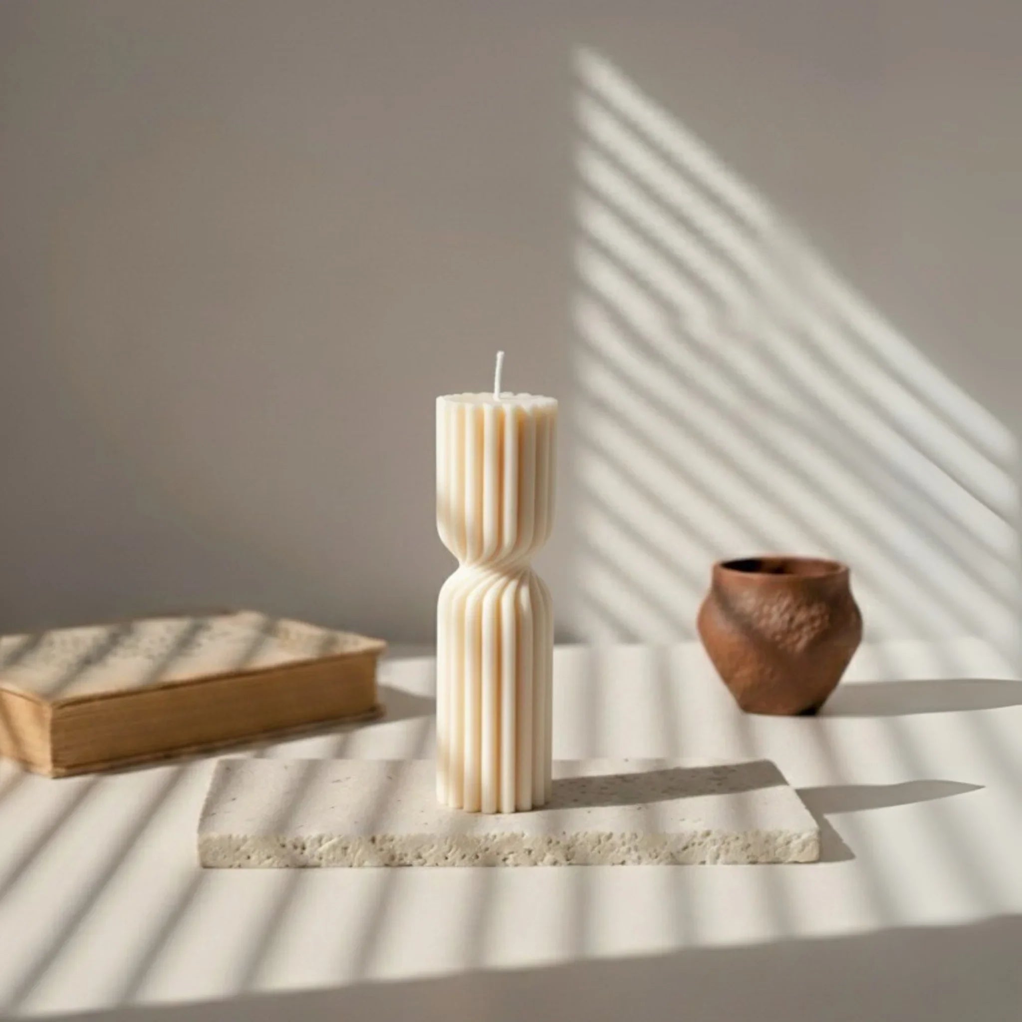 Bougie design blanche sculptée sur support en pierre, décor minimaliste L'Atelier Rochelais