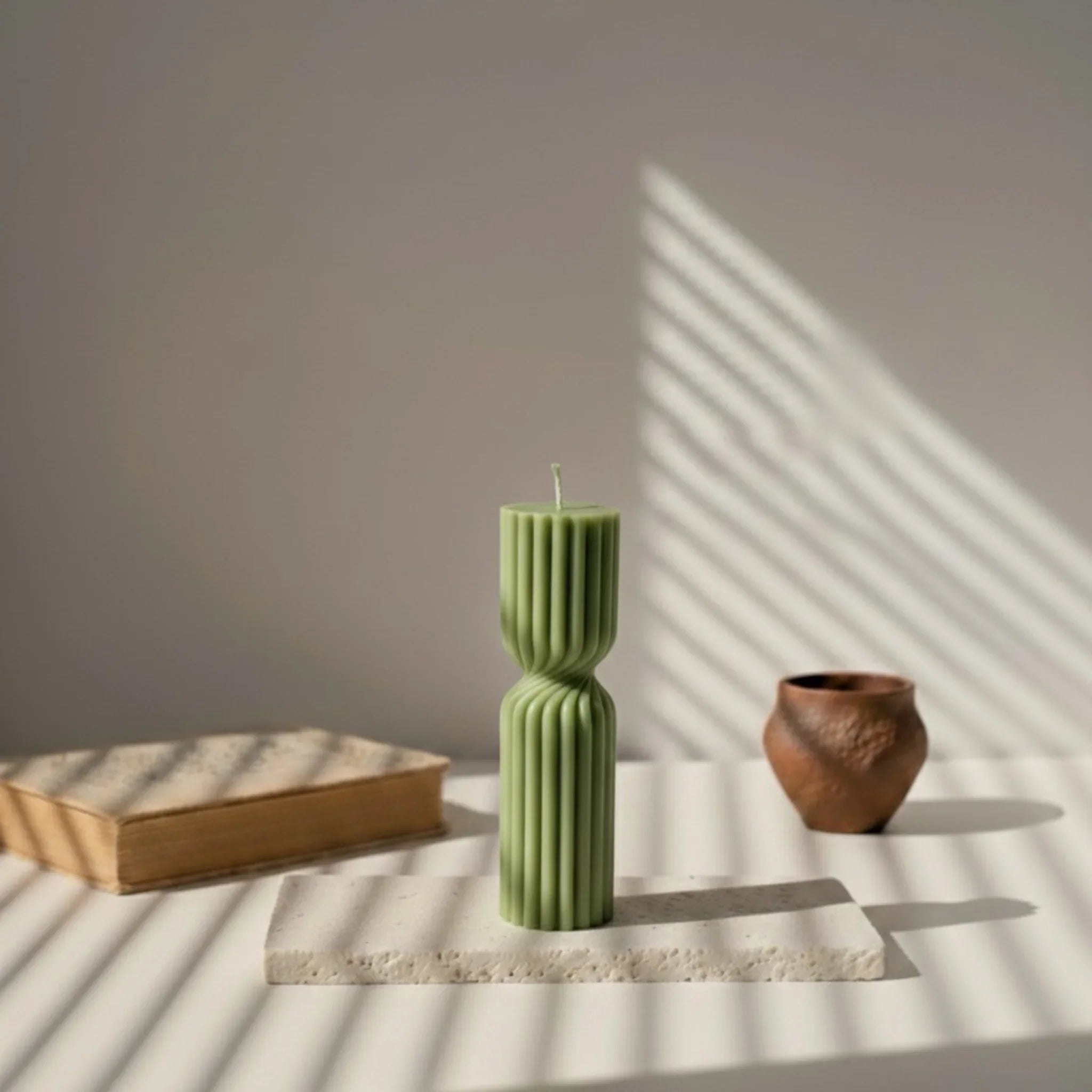 Bougie design vert kaki sur socle, lumière naturelle, décor minimal, L'Atelier Rochelais