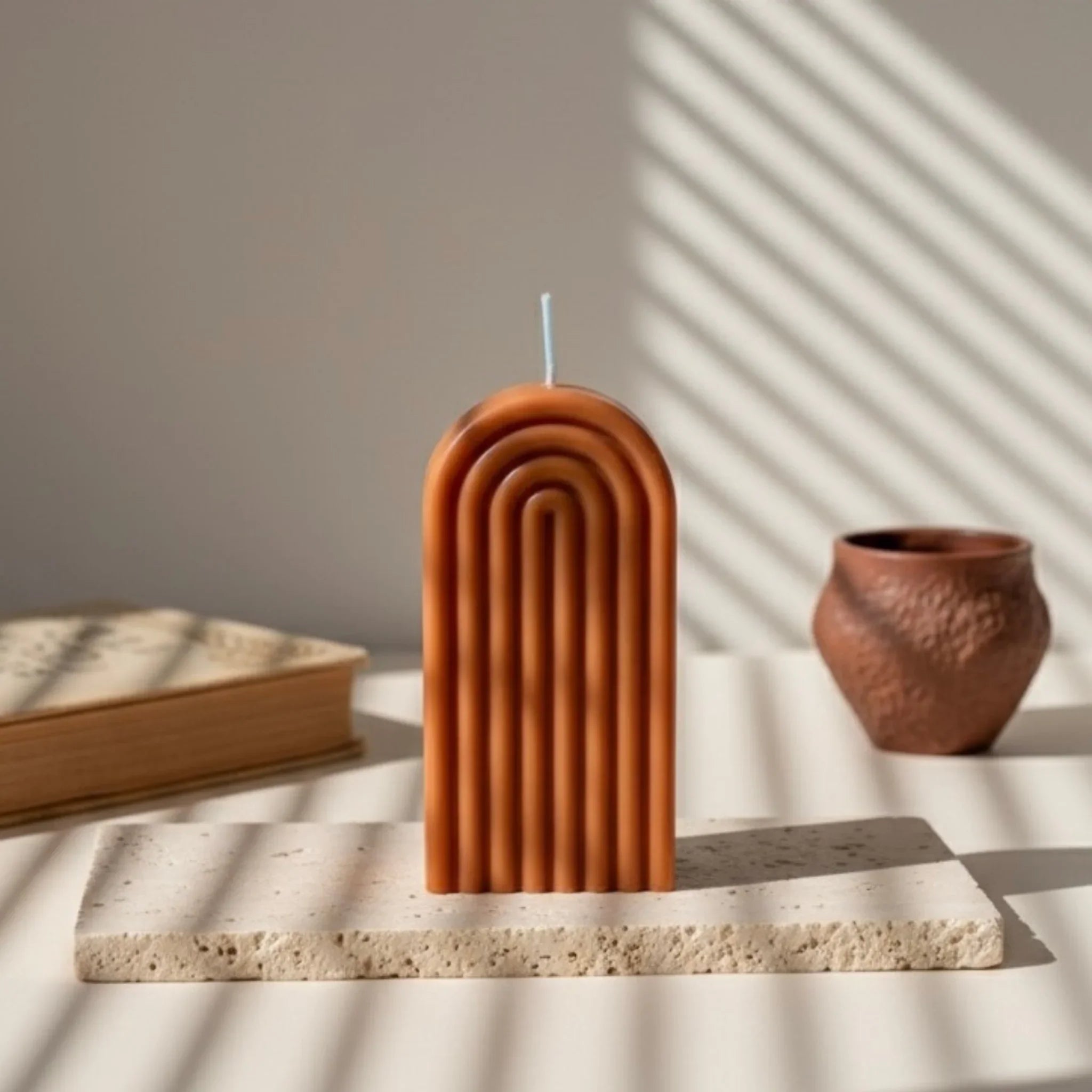 Bougie arche terracotta décorative, posée sur pierre, lumière naturelle, style artisanal.