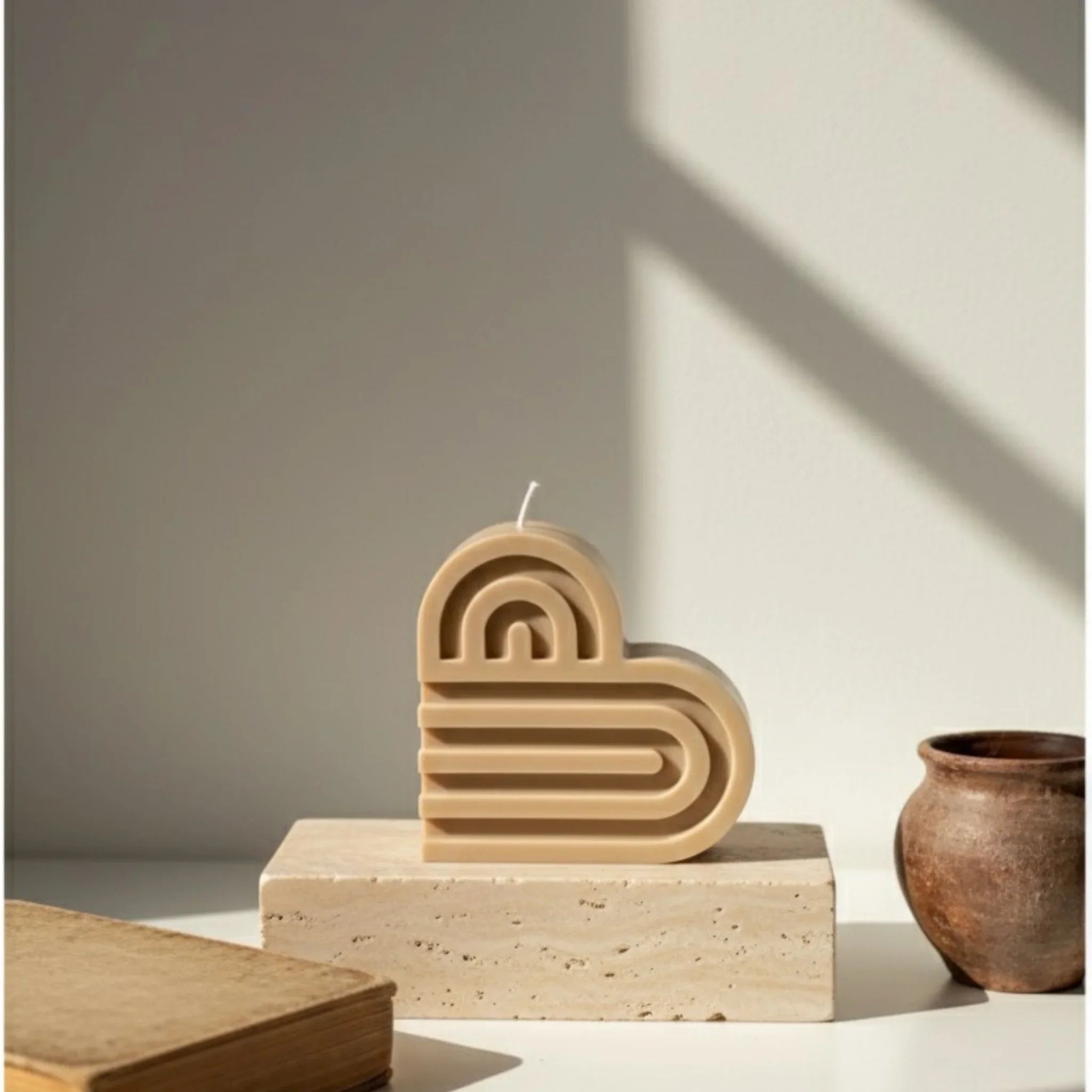 Bougie décorative marron en forme de cœur sur socle, lumière naturelle, style minimaliste