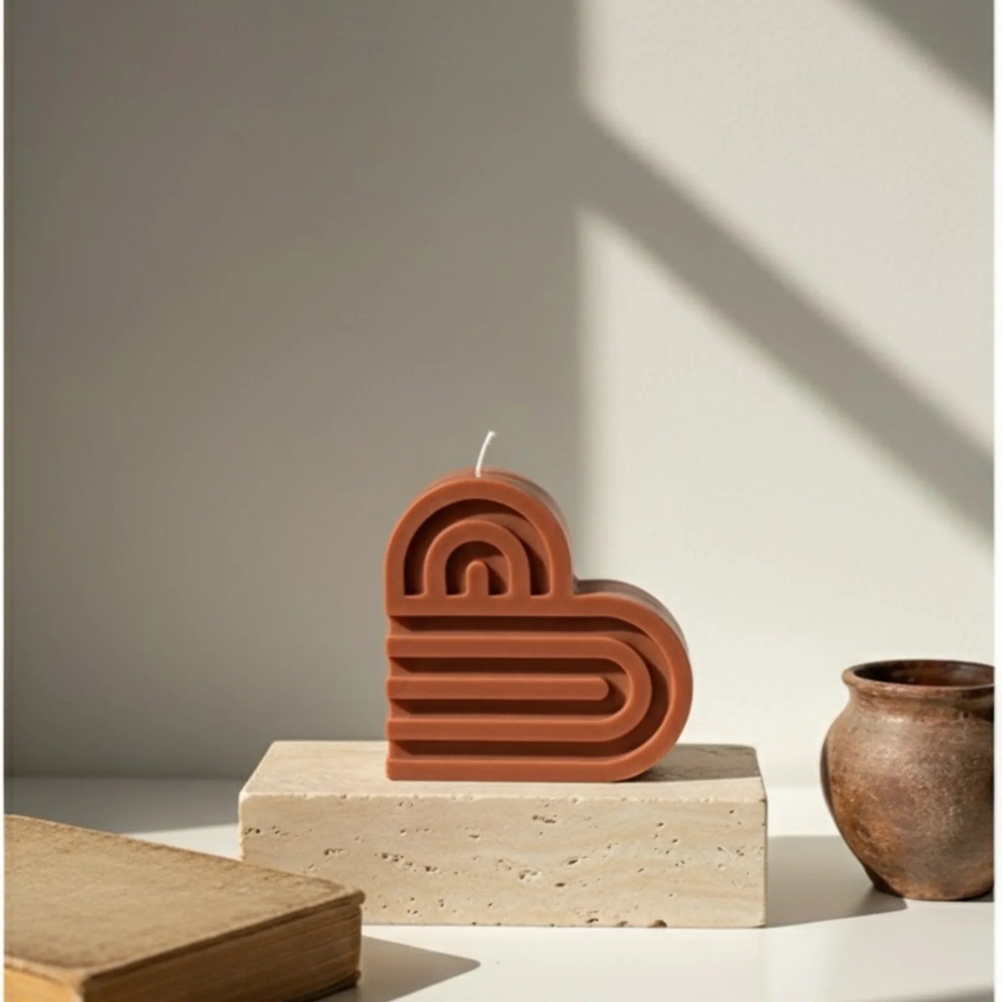 Bougie décorative terracotta en forme de cœur sur socle, style artisanal, lumière naturelle