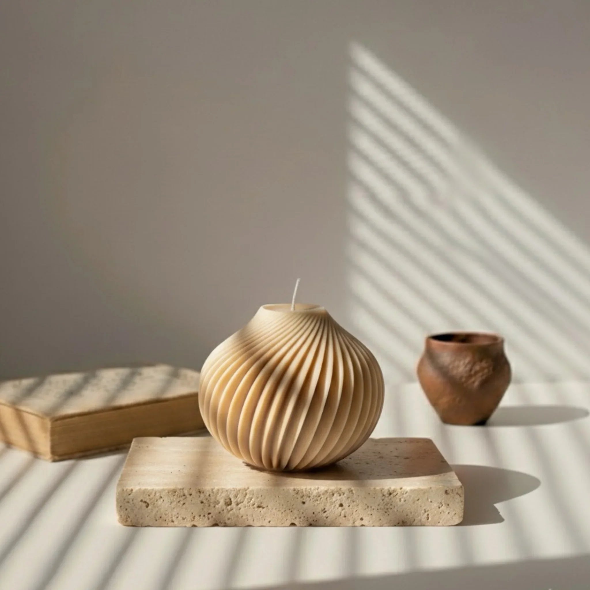 Bougie décorative sphérique marron sur support en pierre, lumière naturelle, style artisanal