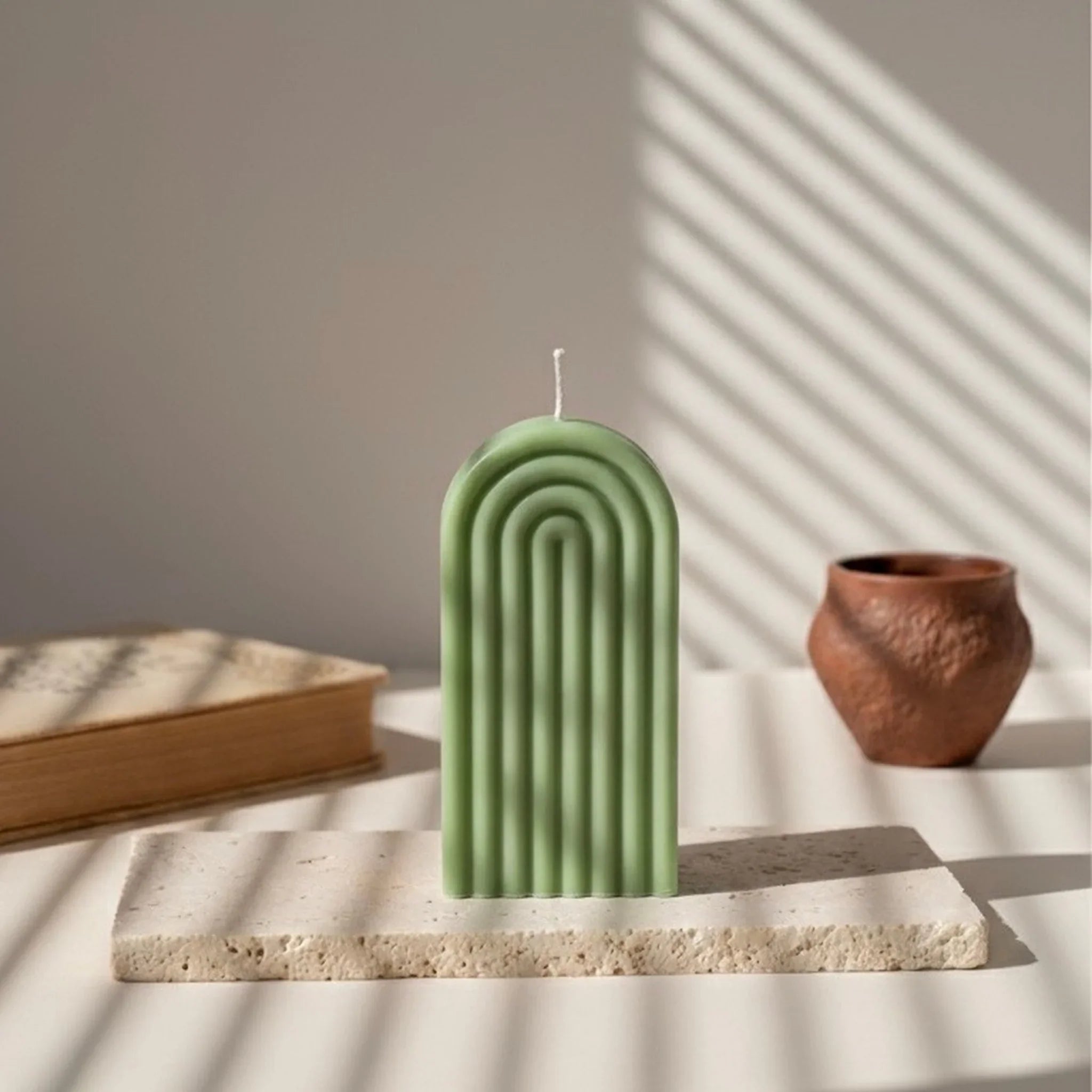 Bougie arche vert kaki posée sur une pierre, décor minimaliste, L'Atelier Rochelais