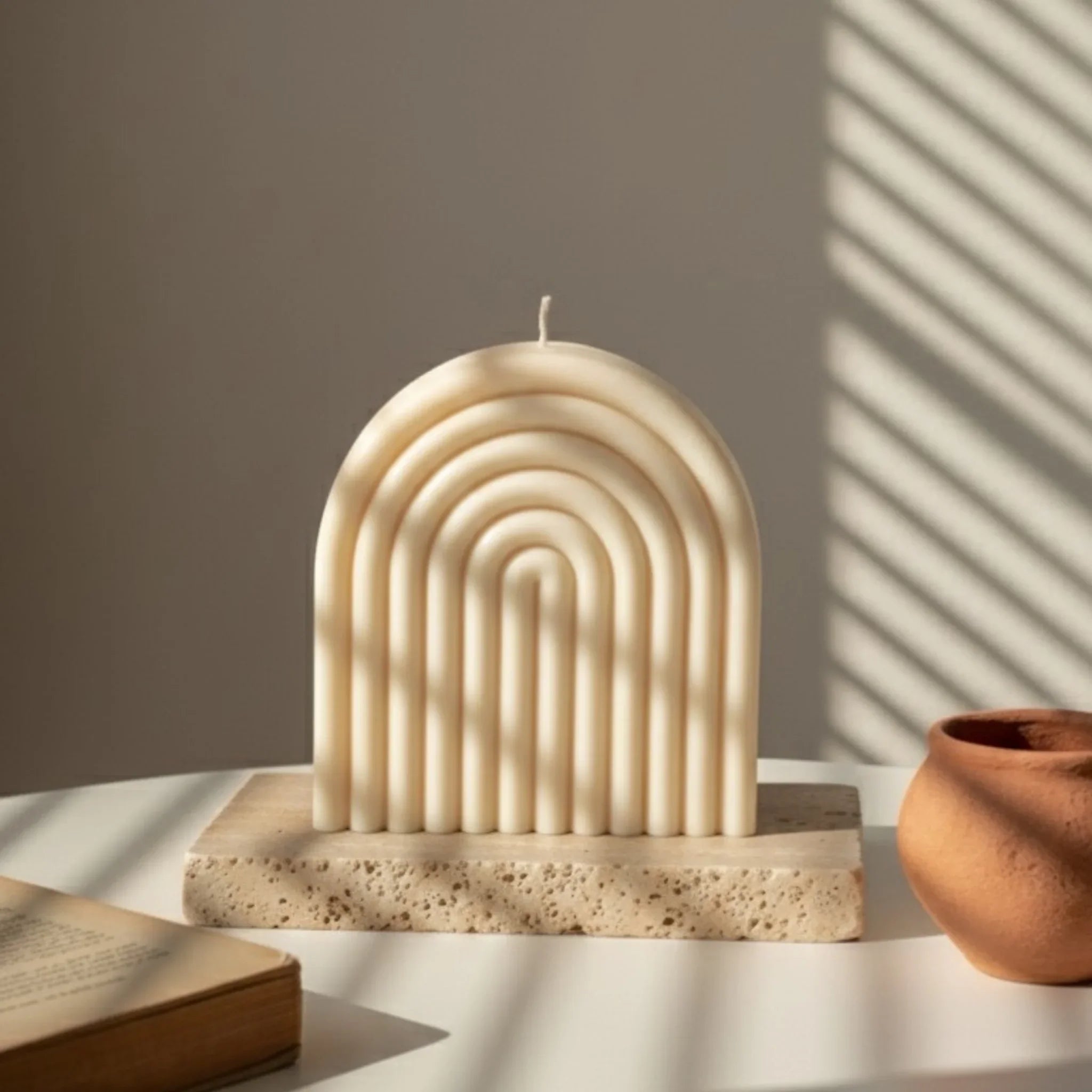 Bougie artisanale ivoire en forme d'arche sur table, lumière naturelle, L'Atelier Rochelais