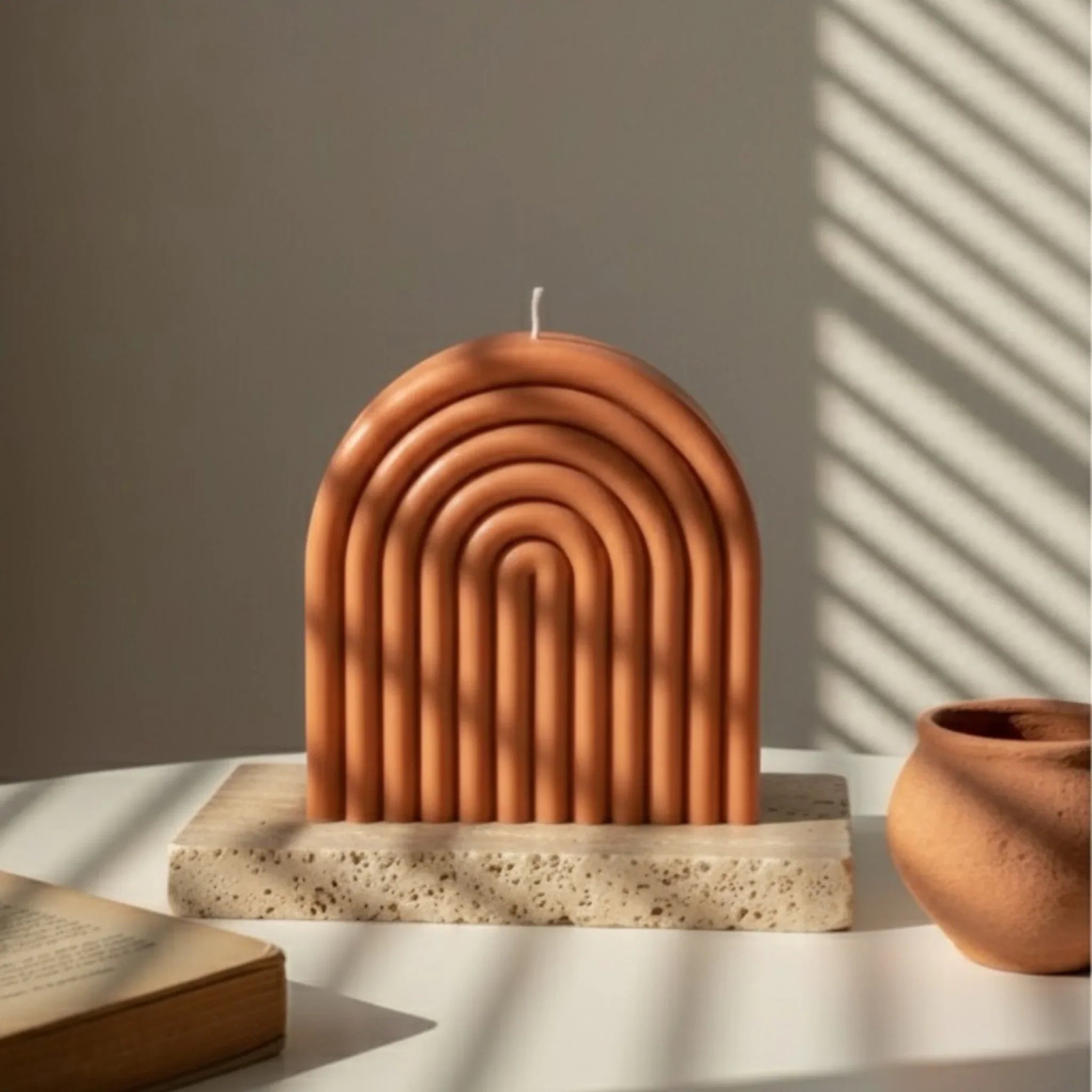 Bougie artisanale en forme d’arche terracotta sur socle en pierre, lumière naturelle, L’Atelier Rochelais