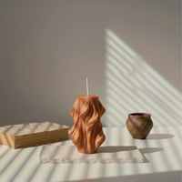 Bougie décorative ondulée couleur terracotta sur table minimaliste, lumière naturelle, L'Atelier Rochelais