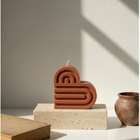 Bougie décorative terracotta en forme de cœur sur socle, style artisanal, lumière naturelle