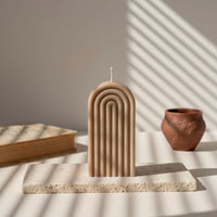 Bougie décorative arche marron sur socle pierre, lumière naturelle, style artisanal élégant